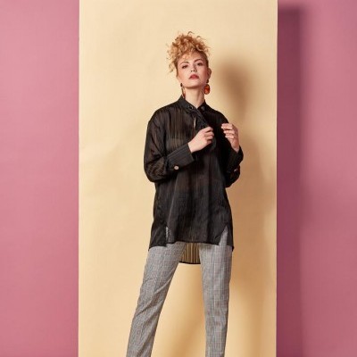 Modelo com blusa preta transparente e calças xadrez cinzentas