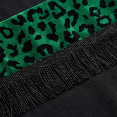 Detalhe de tecido preto com faixa verde estampada e franjas pretas