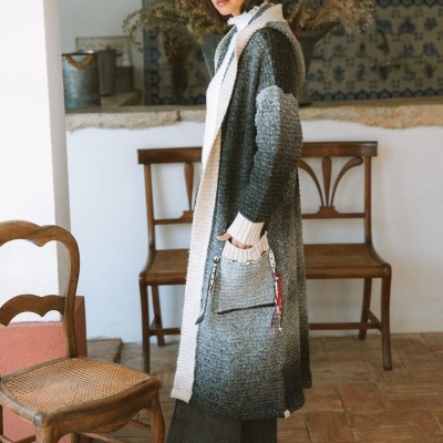 Cárdigan comprido cinza e branco com capuz e bolso frontal, mulher em interior