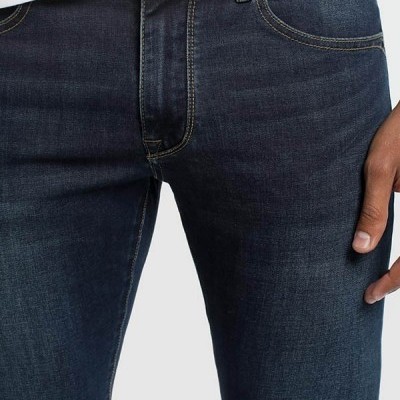 Calças de ganga azuis escuras com costuras amarelas e botão metálico usadas com t-shirt branca