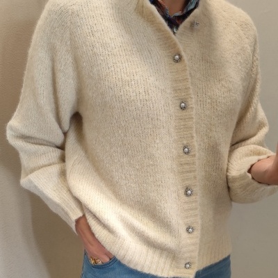 Cárdigan de malha creme com botões decorativos e camisa estampada por baixo