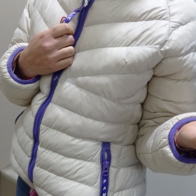 Casaco acolchoado branco com detalhes roxos e fechos com texto PAME