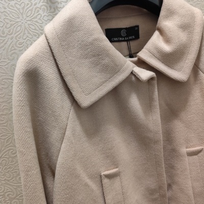 Casaco feminino bege claro com gola ampla pendurado em cabide preto da marca CRISTINA BARROS
