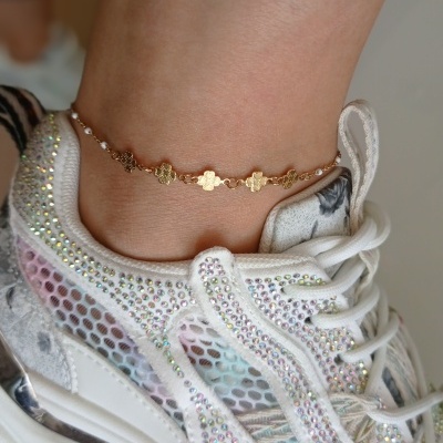 Pulseira dourada em tornozelo com ténis branco brilhante e colorido