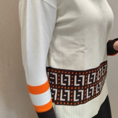 Camisola de malha branca com padrão geométrico castanho e laranja e riscas laranja nas mangas