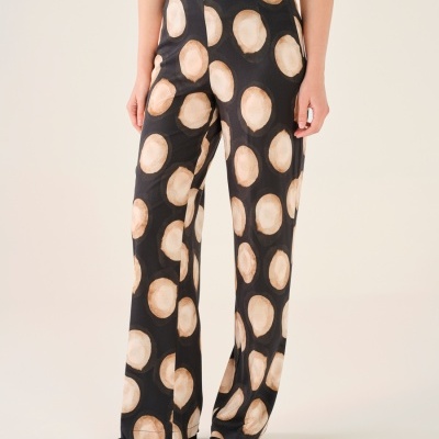 Calças largas com padrão de grandes círculos beige sobre fundo preto