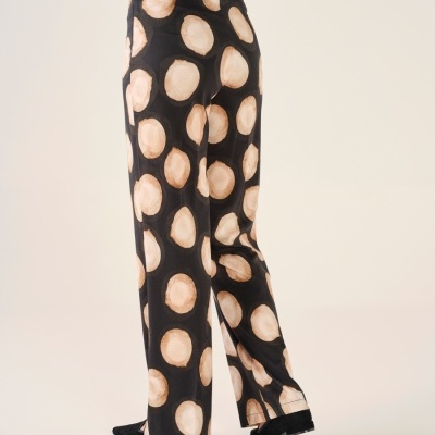 Calças pretas com padrão de círculos bege e castanhos