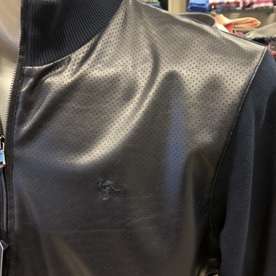 Casaco preto com fecho e textura perfurada na parte da frente.