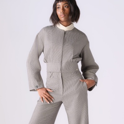 Modelo a veste macacão cinzento riscado com fecho frontal e camisa branca num fundo claro