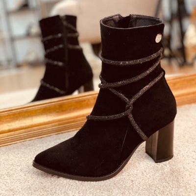 Botim feminino preto com salto quadrado e fitas metálicas prateadas perto de espelho