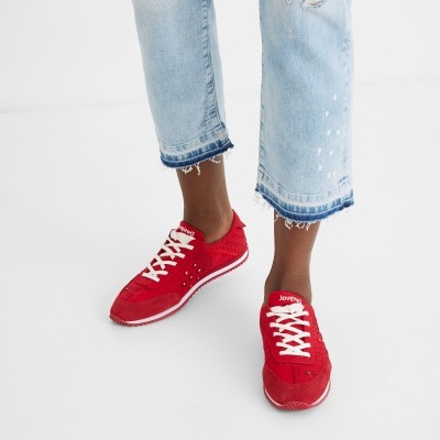 Ténis vermelhos com atacadores brancos e calças de ganga azuis claras com bainha desfiada