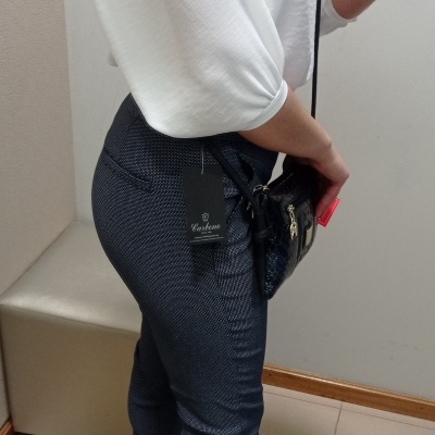 Mulher com blusa branca, calças azul escuro com etiqueta Castelo e sapatos pretos