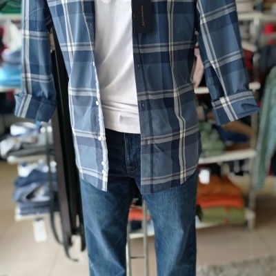Mannequin wearing blue checkered shirt with white undershirt and blue jeans in a store