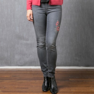 Mulher vestindo calças de ganga cinzentas com bordados vermelhos e botins pretos