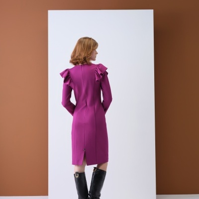 Mulher de costas a usar vestido rosa comprido com folhos nos ombros e botas pretas compridas