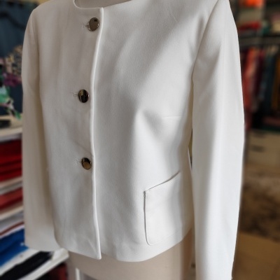 Casaco branco de mulher com botões escuros em manequim