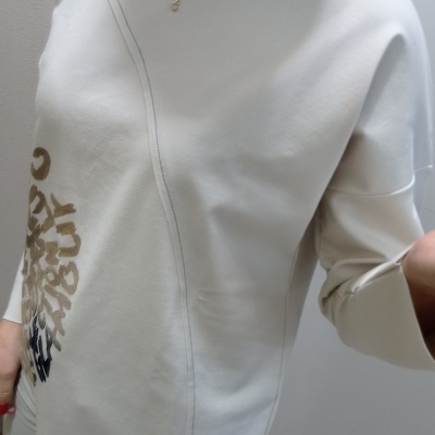 Camisola branca com padrão de letras em tons castanhos e pretos e costura cinzenta.