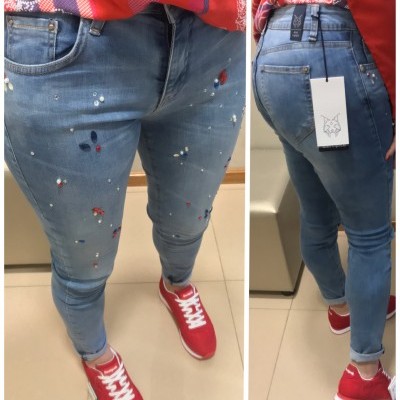 Calças de ganga azuis skinny com detalhes pintados usadas com sapatilhas vermelhas e camisa vermelha