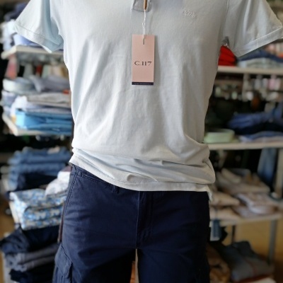 Conjunto masculino com polo azul-claro e calções cargo azul-escuro em manequim na loja