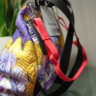 Mala floral com alças pretas e vermelhas em superfície de vidro