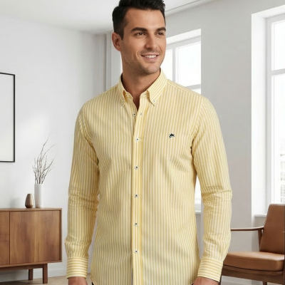 Camisa às riscas amarelas e brancas de algodão com botões, usada por homem em sala moderna