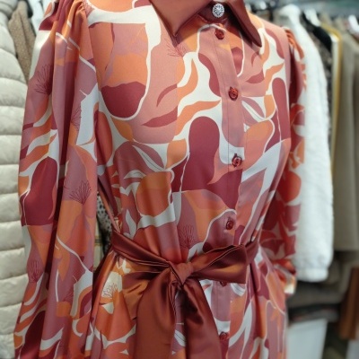 Vestido comprido com padrão abstrato rosa, branco e vermelho com gola, punhos e cinto vermelhos em manequim