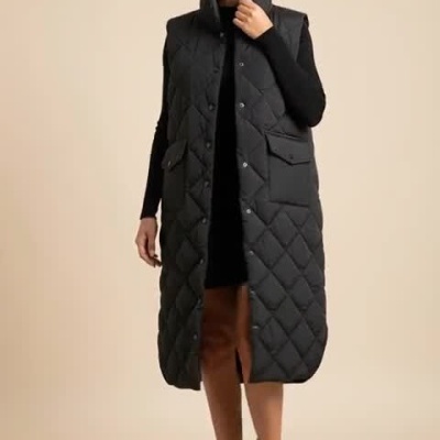 Mulher a usar colete preto longo acolchoado com botões e bolsos grandes