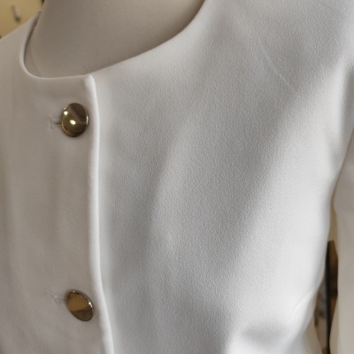 Casaco branco com botões dourados em manequim