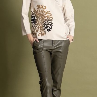 Conjunto blusão bege com padrão circular de texto e calças verde-escuro com botas bege