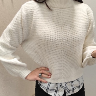 Camisola de malha branca com gola alta e padrão canelado sobre camisa xadrez