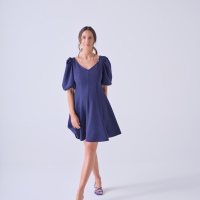 Vestido azul escuro com mangas bufantes e sandálias azuis num fundo branco.