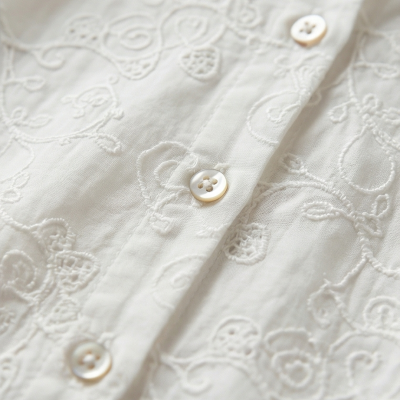 Camisa branca bordada com botões perolados close-up