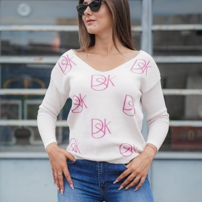 Mulher de óculos escuros com camisola branca estampada e jeans azuis em ambiente urbano