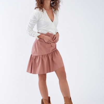 Mulher vestindo blusa branca, saia rosa e botas castanhas com franjas