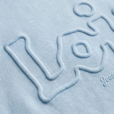Close-up de tecido azul claro com letras em relevo e texto Jean