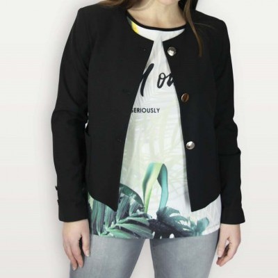 Mulher com camisola branca estampada, casaco preto com botões e calças cinzentas