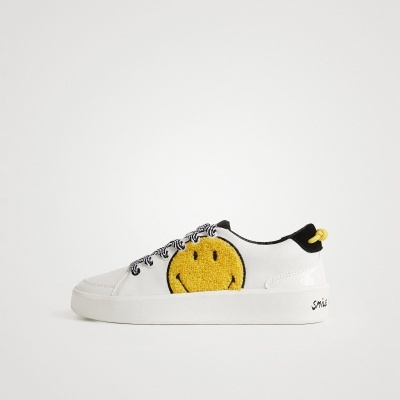 Ténis brancos com smiley amarelo felpudo e atacadores pretos e brancos