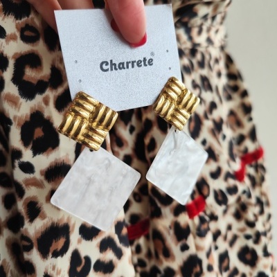 Brincos dourados com pendente branco marmoreado e fundo animal print.