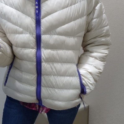 Casaco acolchoado branco com fecho roxo e texto PAME