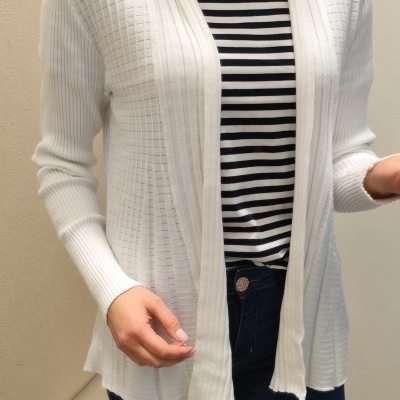 Cardigã branco de tecido malha sobre t-shirt riscada e calças de ganga