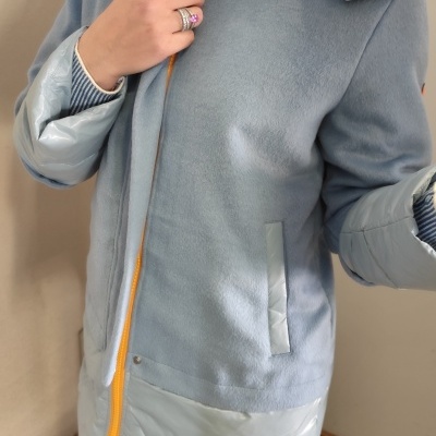 Casaco longo azul claro com capuz e fecho amarelo em modelo