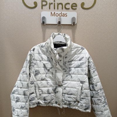 Casaco acolchoado branco e cinza pendurado numa cabide