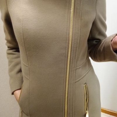 Casaco bege com fechos dourados usados por pessoa em ambiente interior