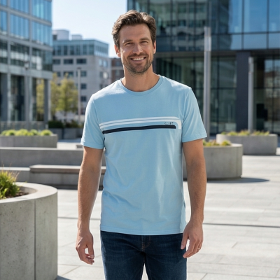 Homem com t-shirt azul clara com riscas e jeans em área urbana moderna