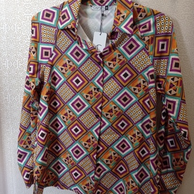 Camisa colorida com padrão geométrico em quadrados coloridos pendurada num cabide preto