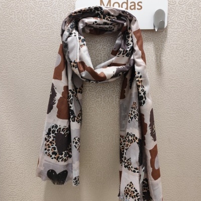 Cachecol com padrão de corações pendurado numa parede decorada.