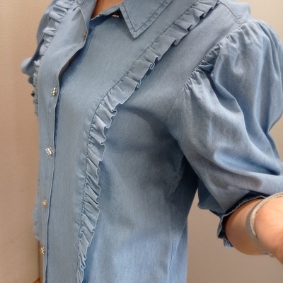 Blusa denim azul claro com folhos e botões metálicos, mangas bufantes