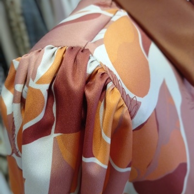 Manga franzida de roupa com padrão floral castanho, branco e amarelo