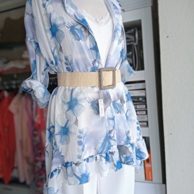 blusa transparente branca com padrão floral azul e cinto bege com fivela quadrada sobre camisa branca de alças