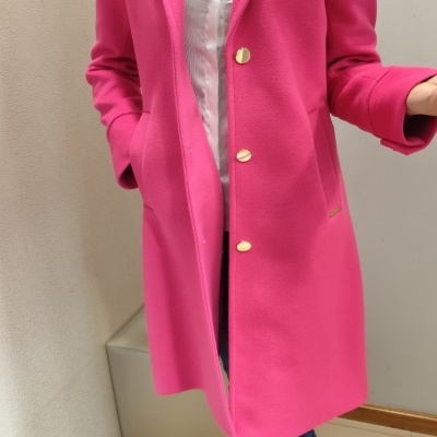 Casaco feminino rosa com botões dourados em ambiente interior